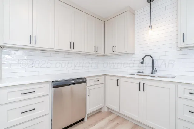 a kitchen with white cabinets and sink