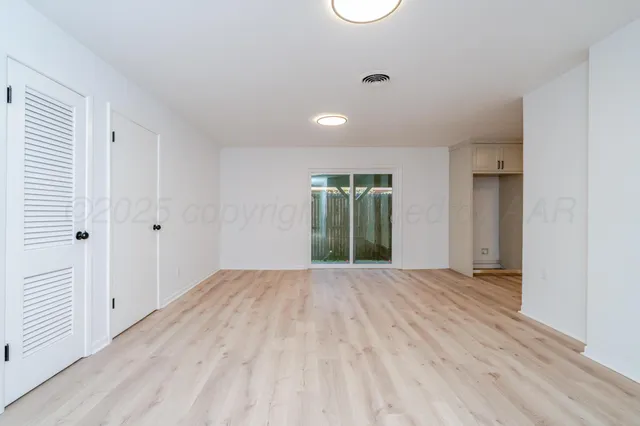 a view of an empty room with glass door and a window