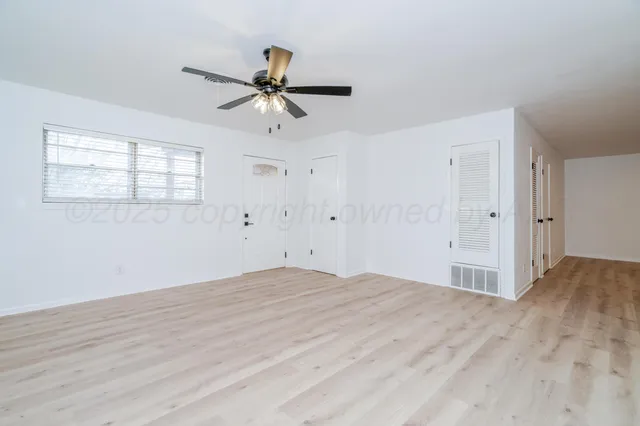 a view of empty room with wooden floor and ceiling fan