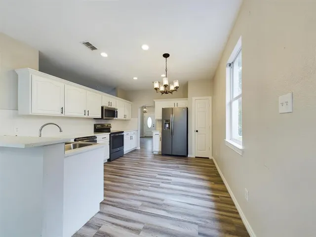 a kitchen with stainless steel appliances kitchen island granite countertop a refrigerator a stove top oven a sink and dishwasher with wooden floor