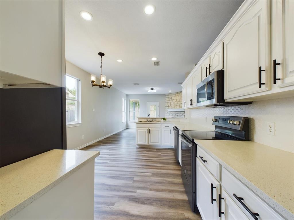 417 Indian Trail Road Roanoke, TX 76262 - Photo 8 of 19 a kitchen with stainless steel appliances granite countertop a refrigerator a stove top oven a sink dishwasher and white cabinets with wooden floor
