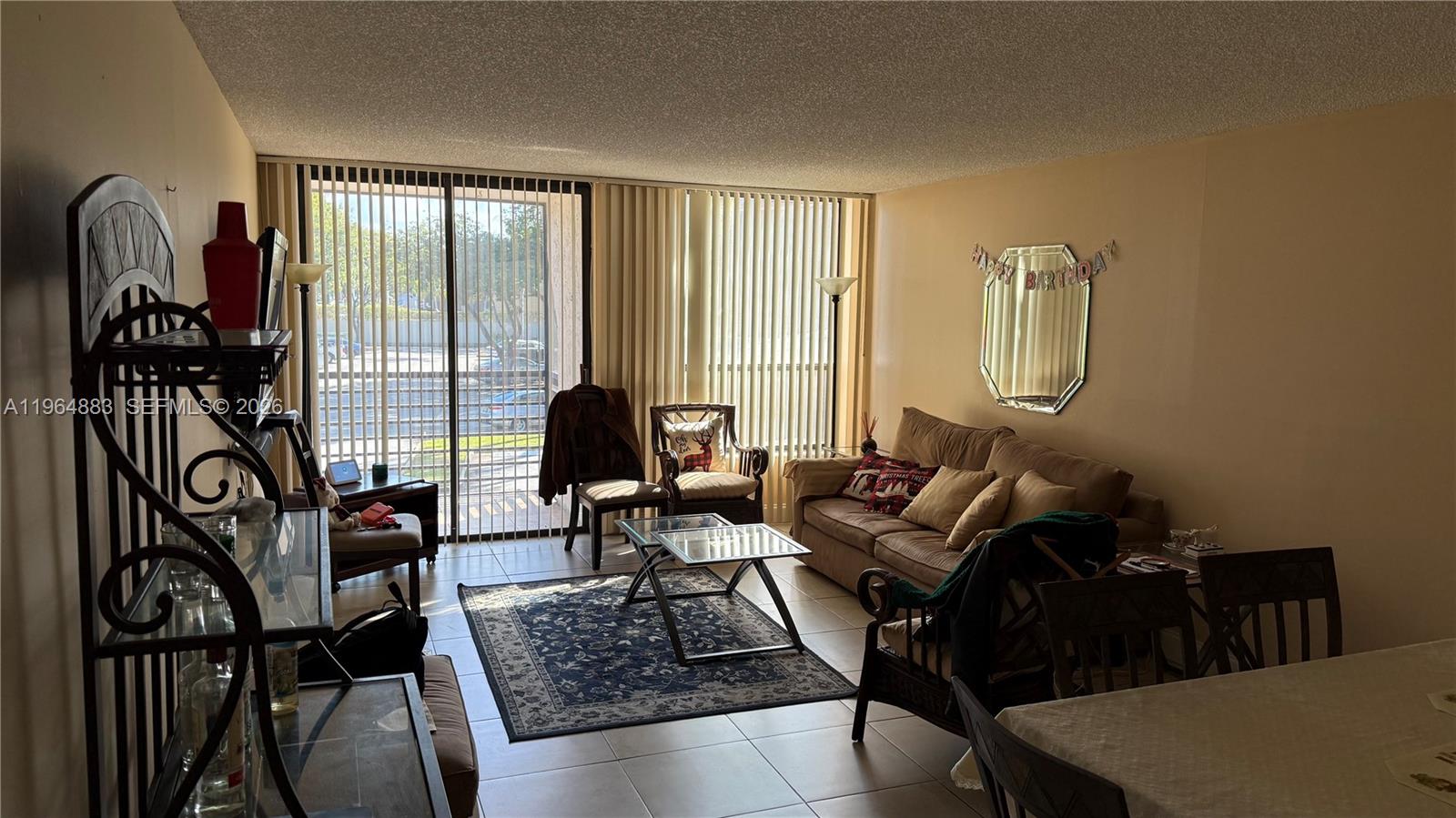 7650 West McNab Road, Unit 201 Tamarac, FL 33321 - Photo 2 of 2 a living room with furniture and a floor to ceiling window