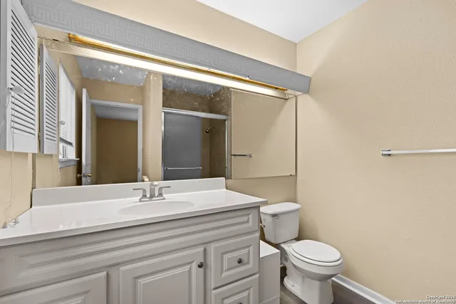 a bathroom with a sink a toilet a mirror and shower