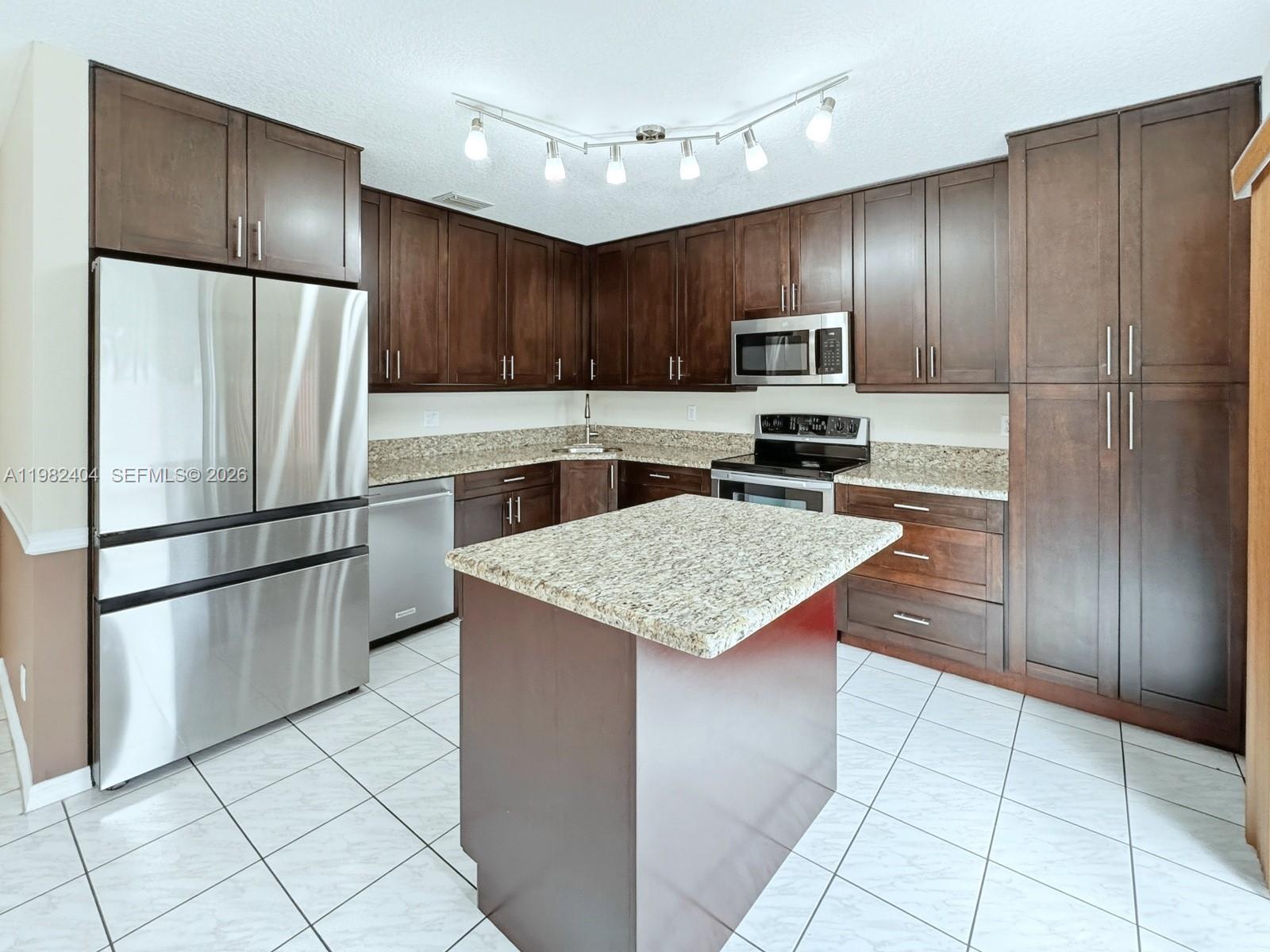 2640 Rampart Way North Cooper City, FL 33026 - Photo 12 of 58 a kitchen with kitchen island granite countertop stainless steel appliances and refrigerator