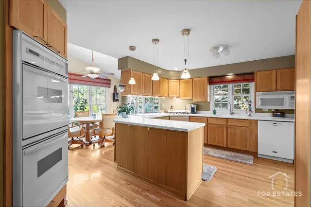 a kitchen with stainless steel appliances granite countertop a refrigerator a sink dishwasher a stove and white cabinets with wooden floor