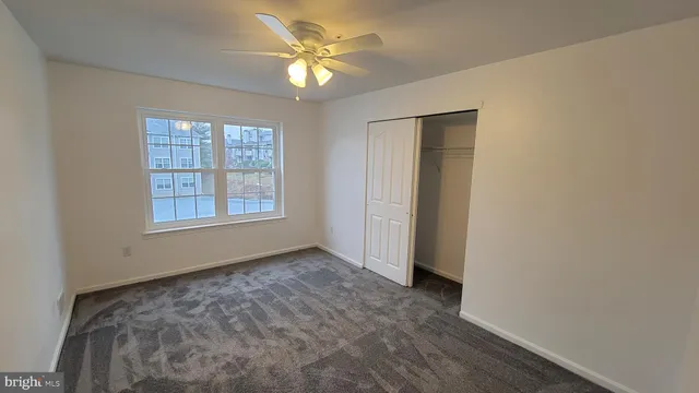 an empty room with windows and ceiling fan