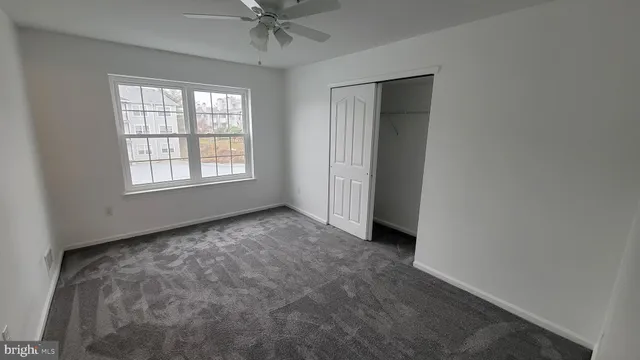 an empty room with chandelier fan and windows