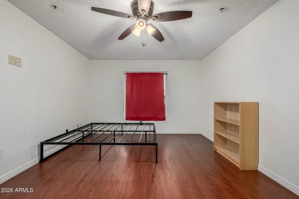 a view of an empty room with a window and wooden floor