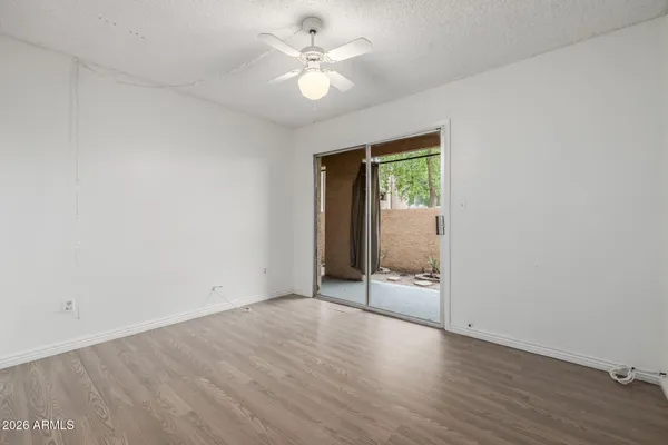 an empty room with wooden floor fan and windows