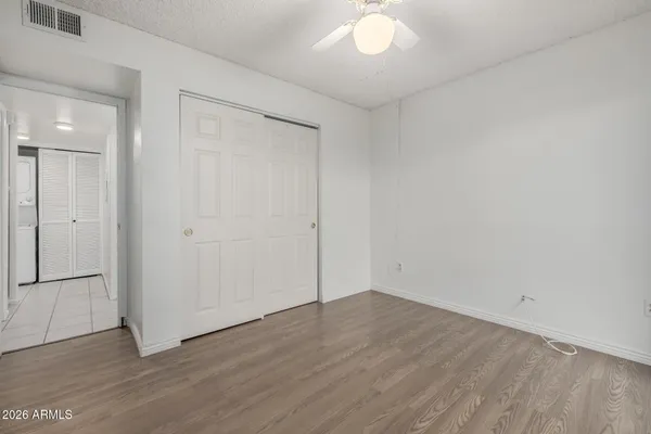 an empty room with wooden floor and a ceiling fan