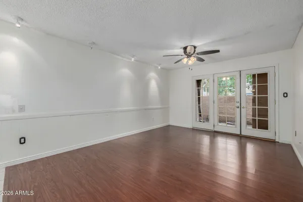 an empty room with wooden floor and a ceiling fan