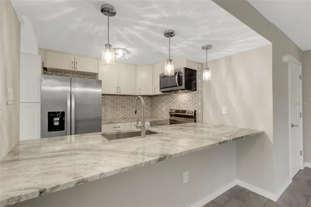 a kitchen with stainless steel appliances granite countertop a sink a refrigerator and a granite counter tops
