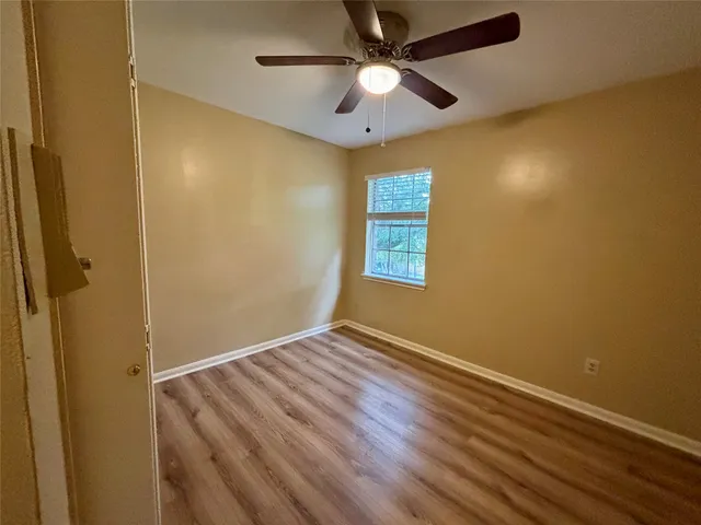 an empty room with a window and a ceiling fan