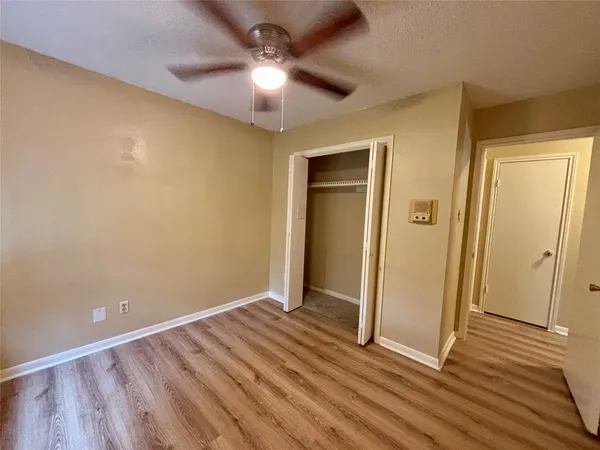 an empty room with wooden floor and fan