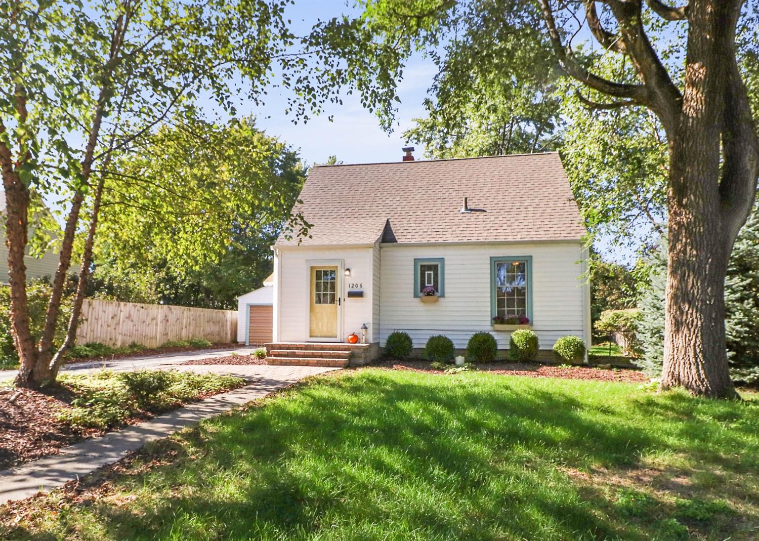 a view of a yard in front of a house with large tree