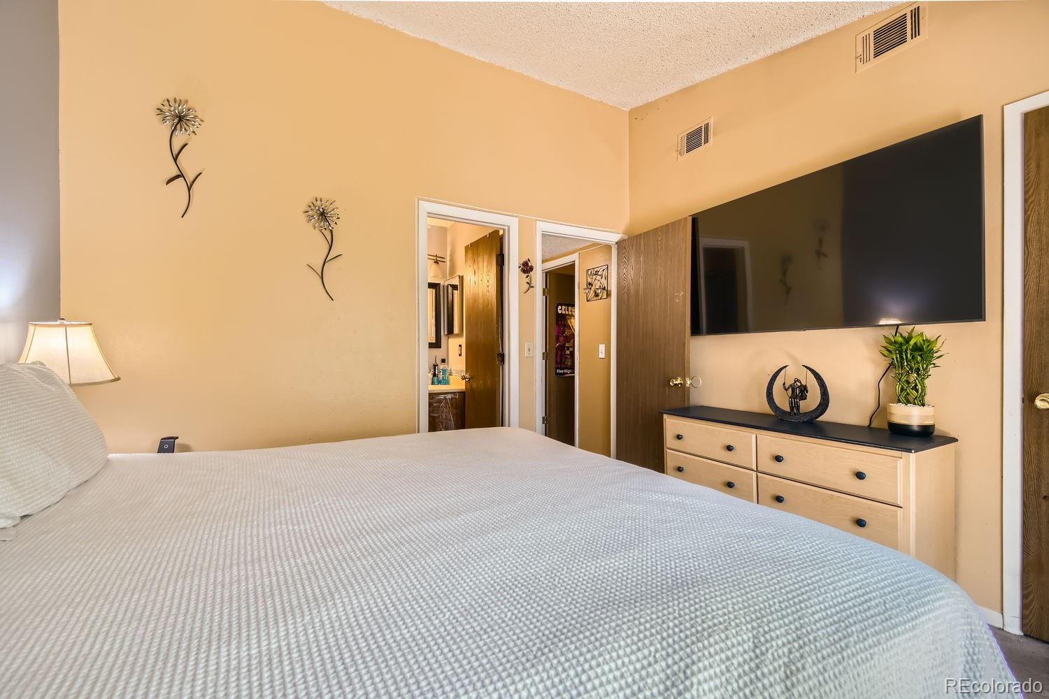 882 South Uravan Court Aurora, CO 80017 - Photo 11 of 33 a bedroom with a bed and a flat screen tv