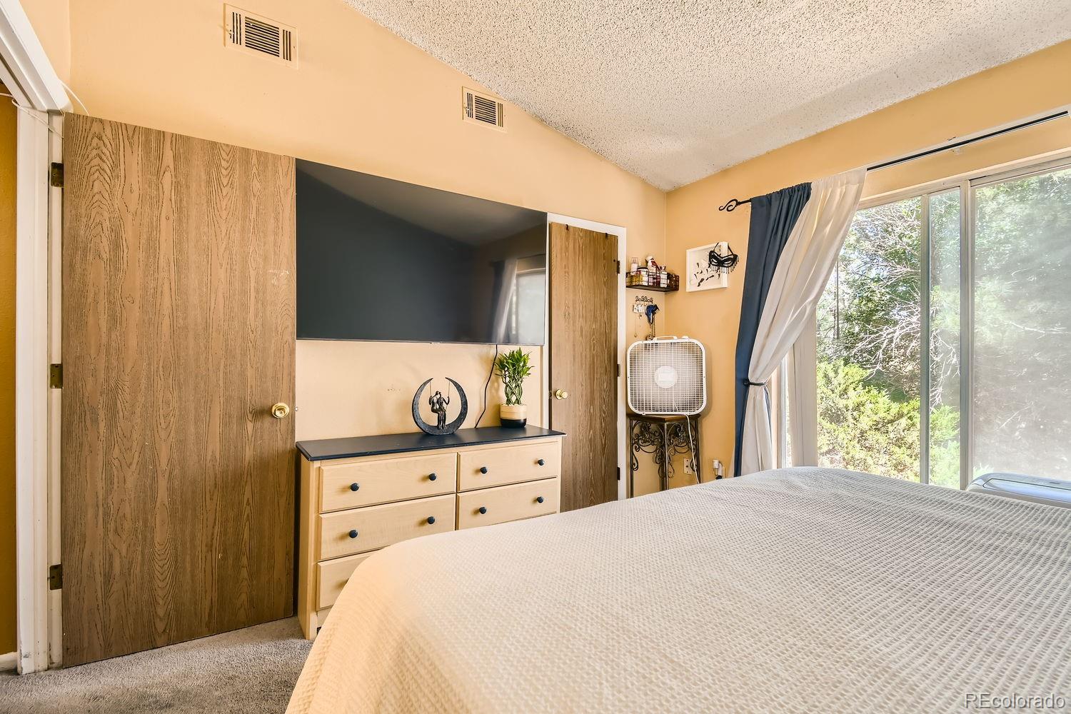 882 South Uravan Court Aurora, CO 80017 - Photo 17 of 33 a bedroom with a bed and a flat tv screen on dresser