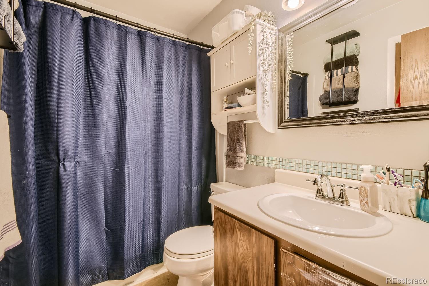 882 South Uravan Court Aurora, CO 80017 - Photo 18 of 33 a bathroom with a sink a toilet a mirror and shower curtain