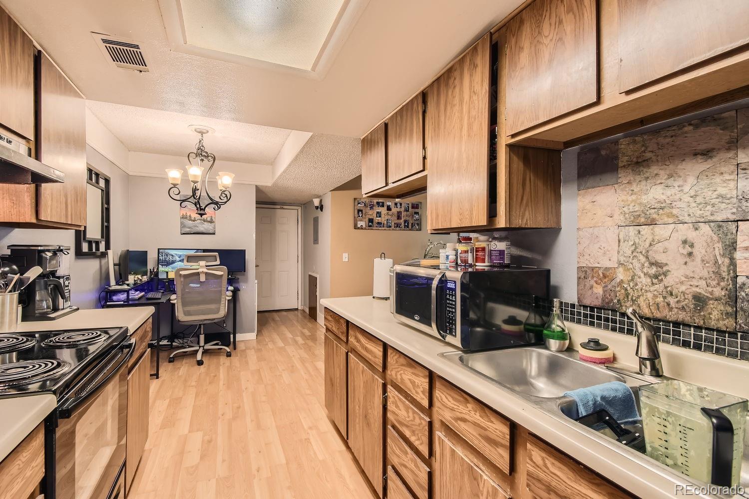 882 South Uravan Court Aurora, CO 80017 - Photo 8 of 33 a kitchen with stainless steel appliances kitchen island granite countertop a sink stove and cabinets