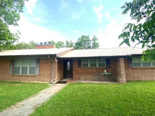 a view of a house with a yard and front a large tree