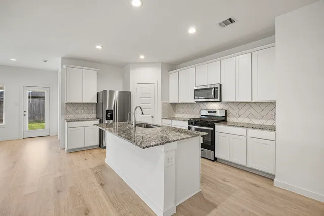 a kitchen with granite countertop a sink stove and refrigerator