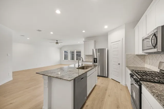 a kitchen with stainless steel appliances granite countertop a sink stove and refrigerator
