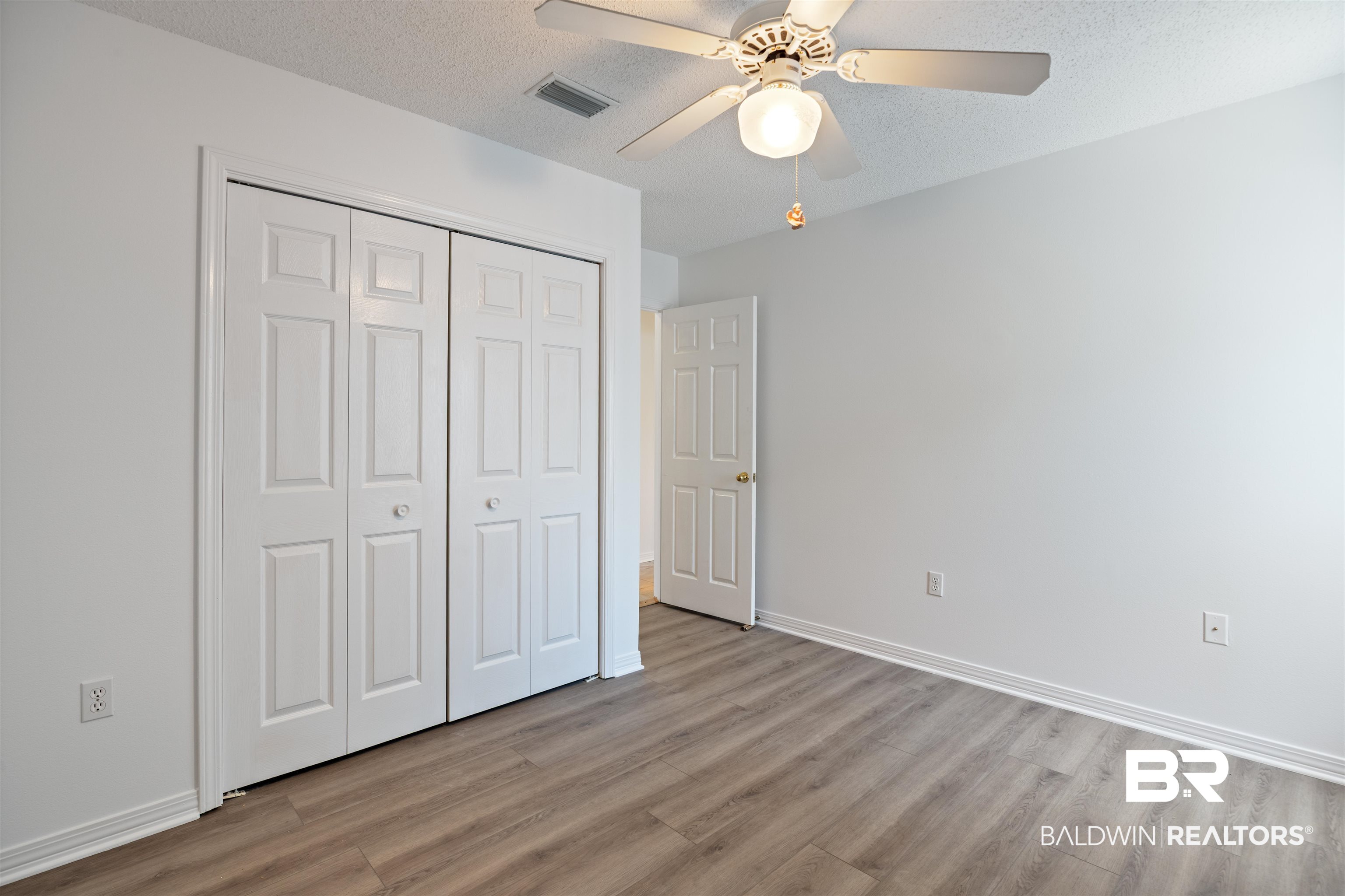 3200 Loop Road, Unit 96 Orange Beach, AL 36561 - Photo 31 of 49 Room featuring wood-finish flooring, a ceiling fan with integrated lighting, and a white six-panel door