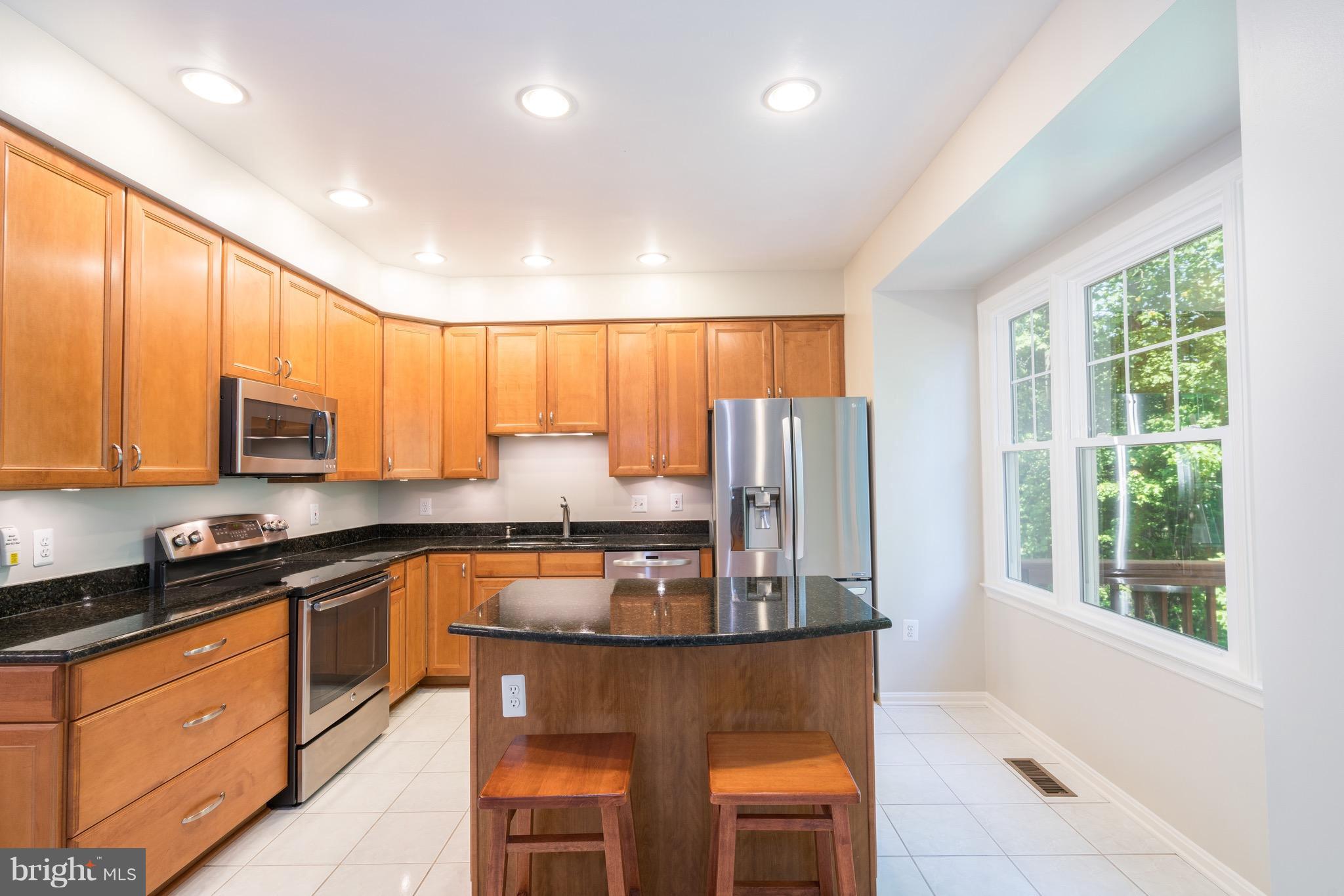 1211 Weatherstone Court Reston, VA 20194 - Photo 7 of 30 a kitchen with stainless steel appliances granite countertop wooden cabinets a stove top oven a sink and dishwasher a refrigerator with wooden floor
