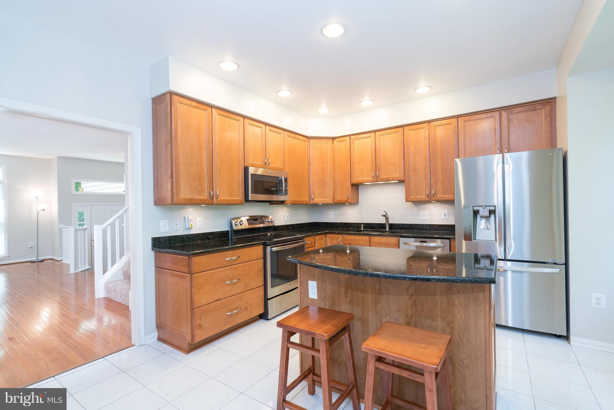 1211 Weatherstone Court Reston, VA 20194 - Photo 8 of 30 a kitchen with stainless steel appliances granite countertop a refrigerator a stove a sink a dining table and chairs with wooden floor