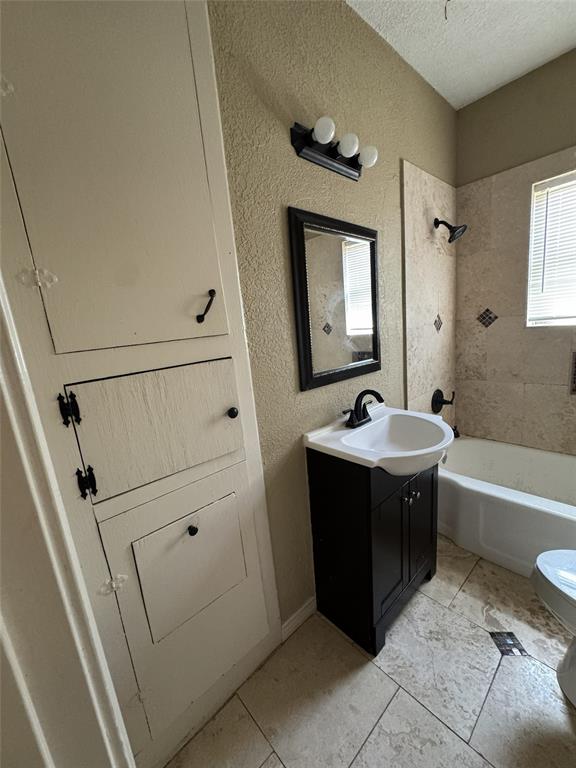 803 Ripley Avenue Ennis, TX 75119 - Photo 32 of 40 Bathroom featuring a dark wood-finish vanity with a white basin, an integrated bathtub and shower with tiled surround, and light-toned tile flooring