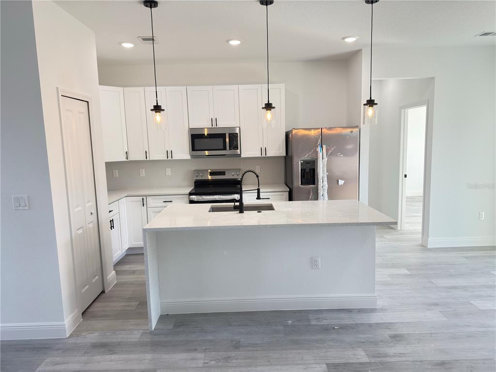 4650 Southwest 139th Place Ocala, FL 34473 - Photo 6 of 49 a kitchen with stainless steel appliances a refrigerator a sink a stove a kitchen island and chairs with wooden floor