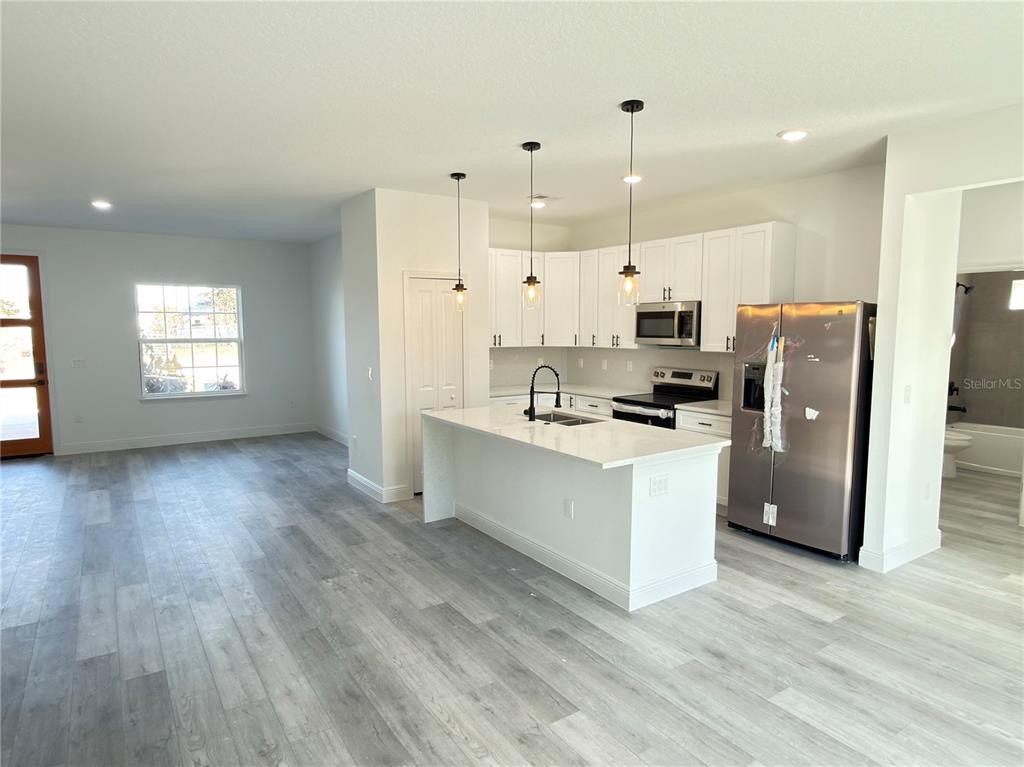 4650 Southwest 139th Place Ocala, FL 34473 - Photo 8 of 49 a kitchen with stainless steel appliances a refrigerator a stove a sink cabinets and wooden floor