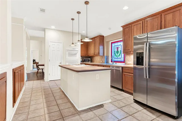 a kitchen with stainless steel appliances granite countertop a refrigerator a oven and a sink