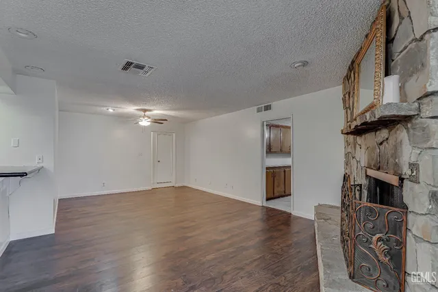 a view of an empty room with wooden floor and a fireplace