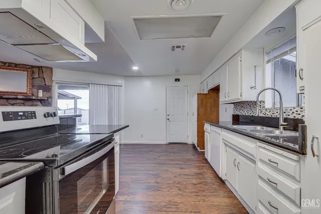 a kitchen with stainless steel appliances granite countertop a stove sink and cabinets