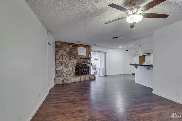 a view of a livingroom with a fireplace a ceiling fan and wooden floor