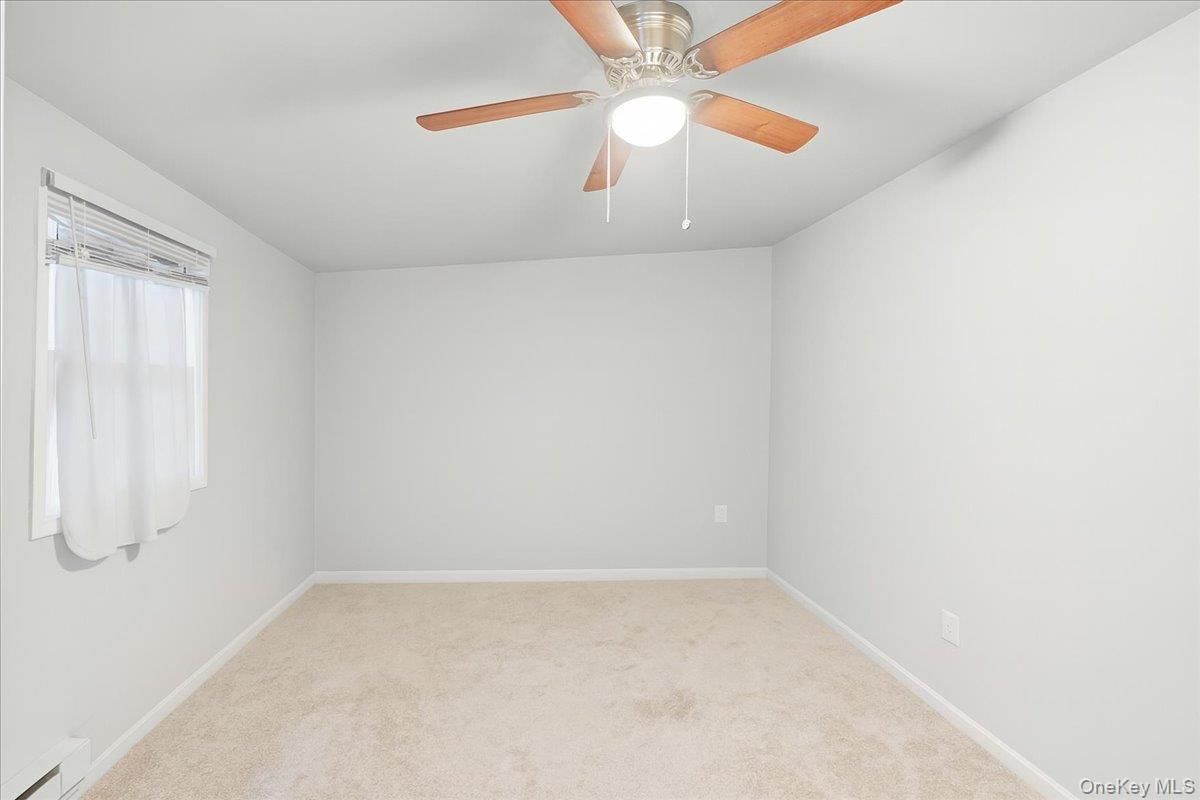30 George Drive Mastic, NY 11950 - Photo 18 of 26 an empty room with a window and a fan