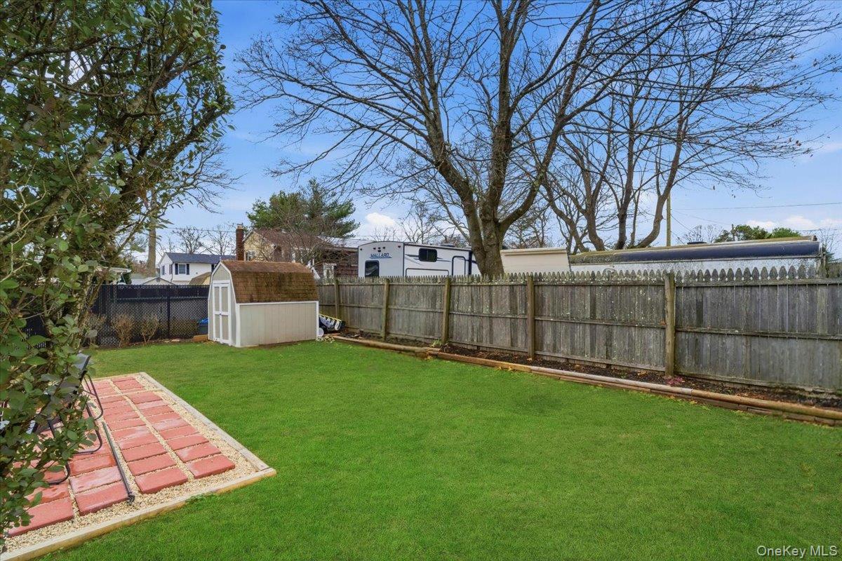 30 George Drive Mastic, NY 11950 - Photo 24 of 26 a view of a backyard with a fence and trees