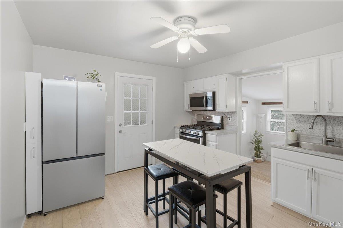 30 George Drive Mastic, NY 11950 - Photo 10 of 26 a kitchen with stainless steel appliances granite countertop a refrigerator a sink a stove a dining table and chairs
