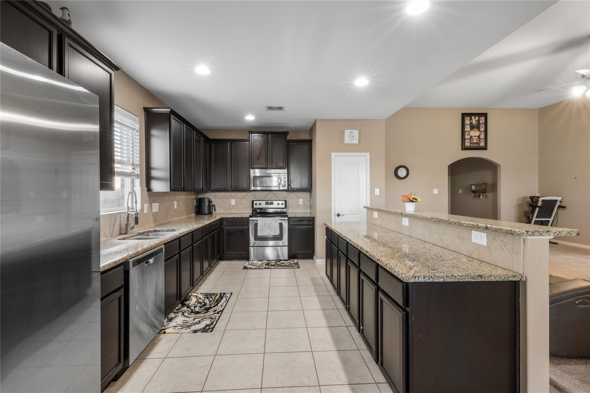 22907 Gentle Shadow Drive Hockley, TX 77447 - Photo 10 of 27 a large kitchen with stainless steel appliances kitchen island granite countertop a counter top a sink and cabinets