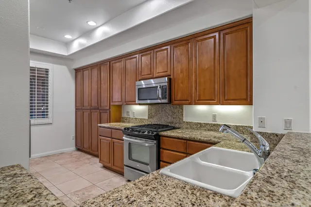a kitchen with granite countertop stainless steel appliances a stove a sink and a refrigerator