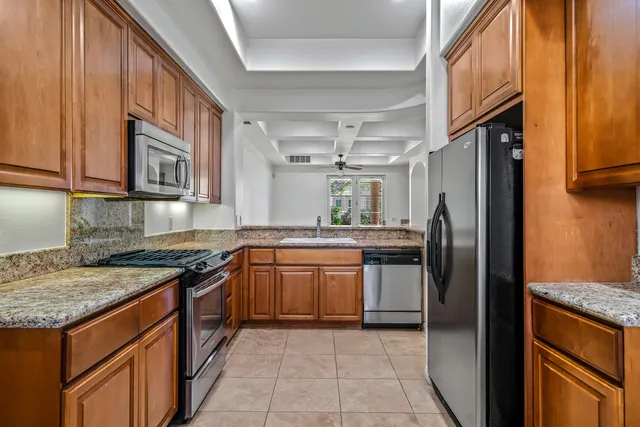 a kitchen with stainless steel appliances granite countertop a refrigerator a stove and a sink