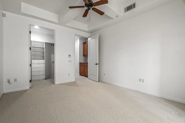 an empty room with closet and a ceiling fan