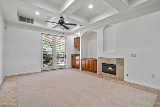 an empty room with windows fireplace and a kitchen view