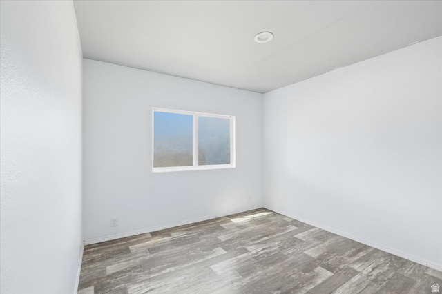 433 North 750 West Logan, UT 84321 - Photo 20 of 40 Light-filled room featuring wood-finish flooring, a single window with white trim, recessed ceiling lighting, and smooth white walls