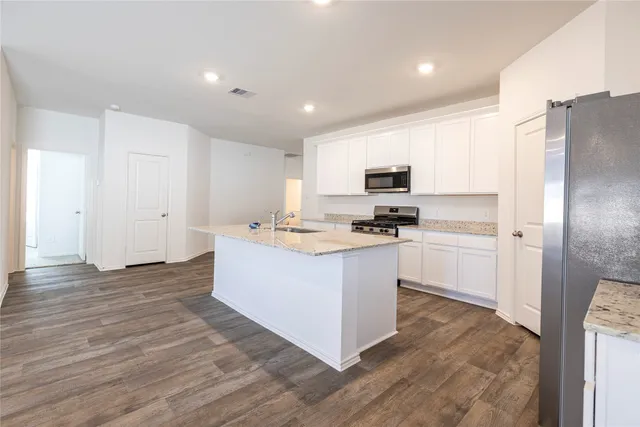 a kitchen with stainless steel appliances granite countertop a refrigerator oven a sink a stove with wooden floors and cabinets