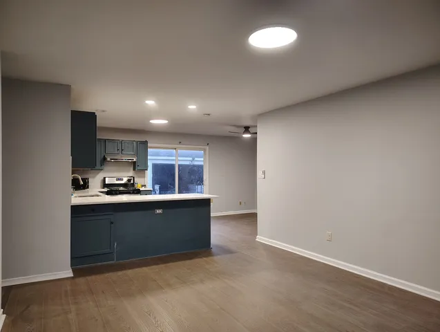 an empty room with wooden floor chandelier fan and windows