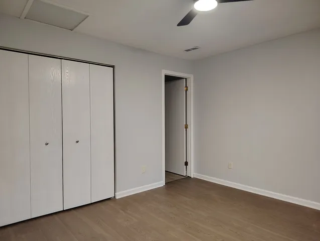an empty room with wooden floor cabinet and windows