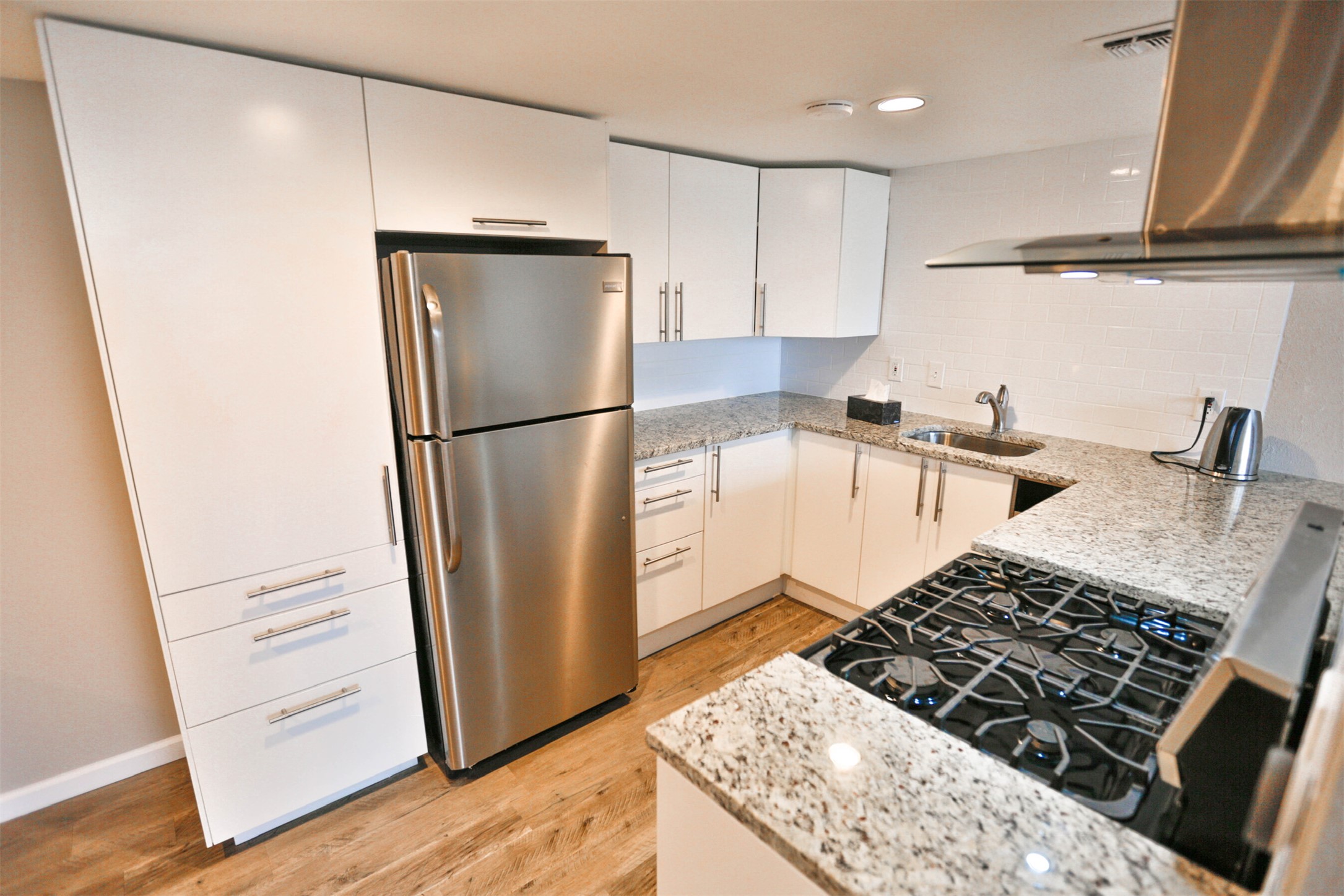 1800 Lavaca Street, Unit A608 Austin, TX 78701 - Photo 8 of 12 Kitchen featuring light stone countertops, exhaust hood, freestanding refrigerator, white cabinetry, and recessed lighting