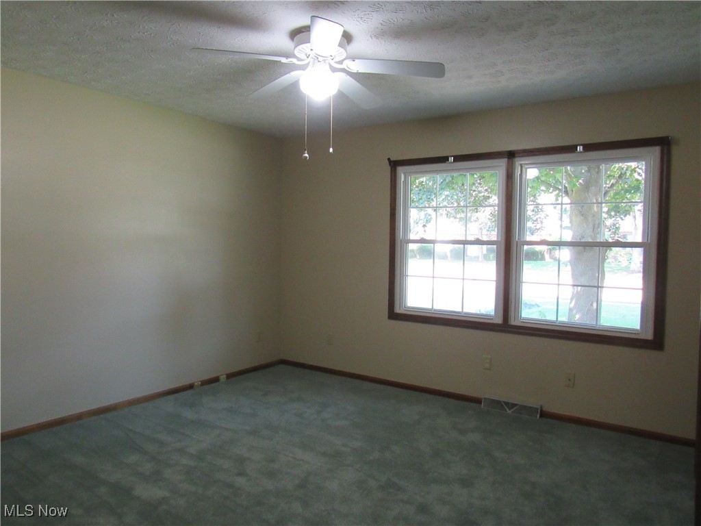 1120 Vincent Road Southeast North Canton, OH 44720 - Photo 39 of 50 Front bedroom with ceiling fan, a textured ceiling, and new carpet